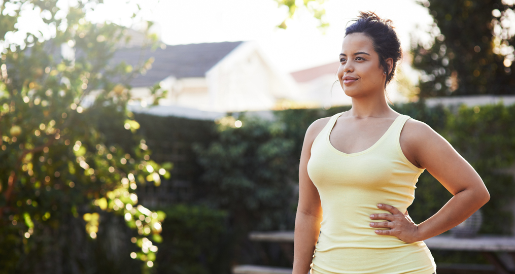 woman in workout clothes standing in her back yard