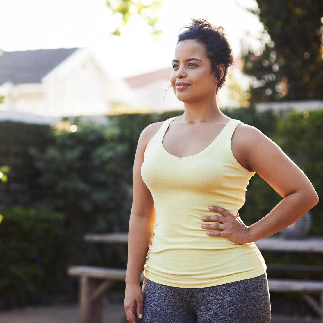 woman in workout clothes standing in her back yard