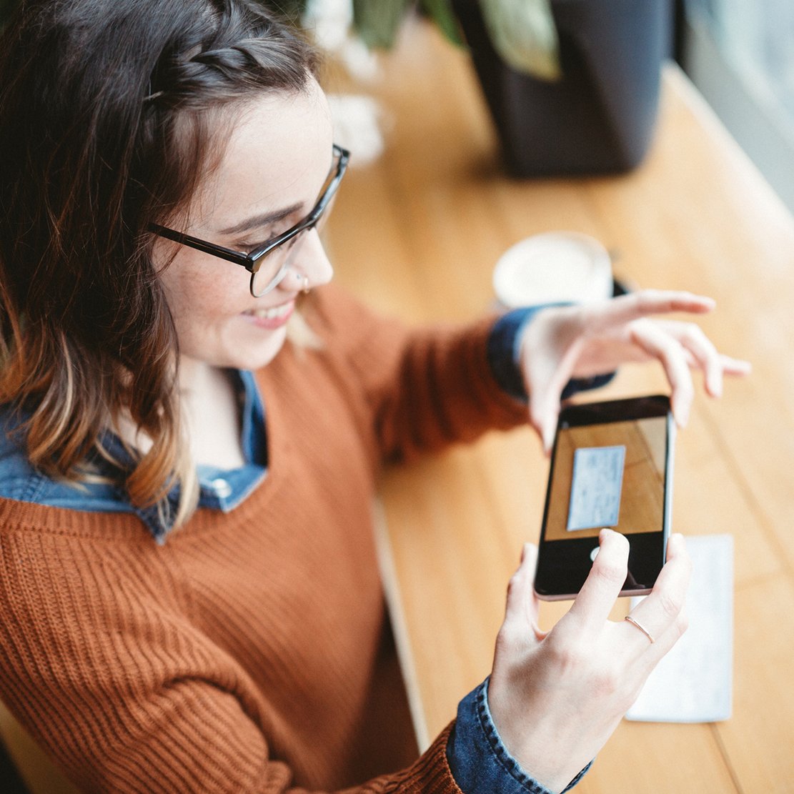 woman smiling while using her phone to deposit a check