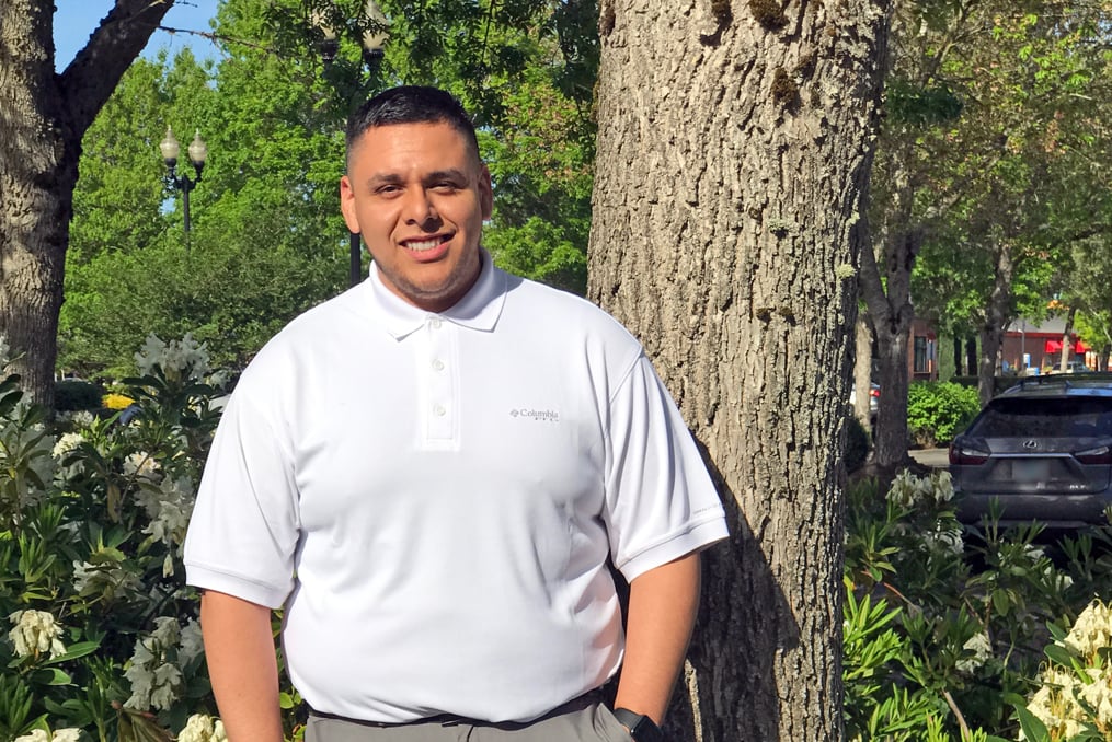 James Fuentes standing near a tree and some flowers outside the Orenco Station Branch