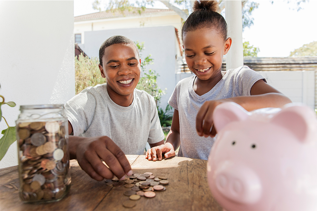 OnPoint Savers Account_two siblings counting coins from their change jar and piggy bank