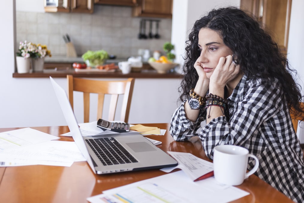 woman looking stressed while reviewing her finances after falling victim to a sweetheart scam