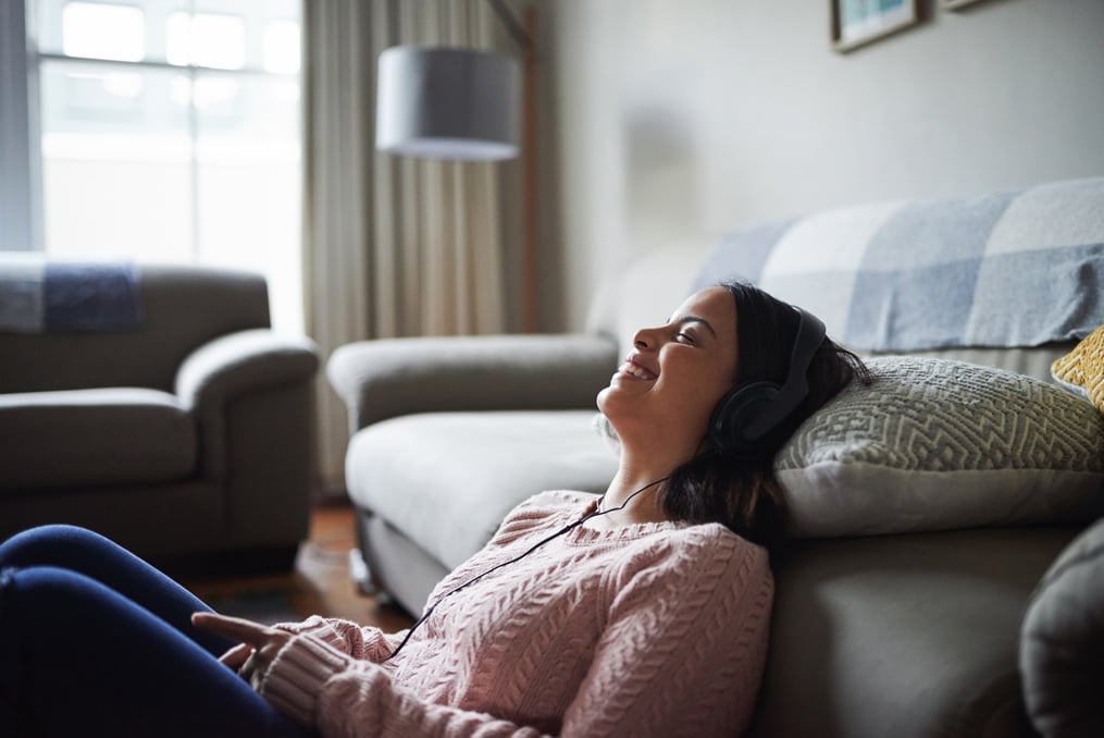 woman sitting on the floor in her living room relaxing and enjoying listening to music