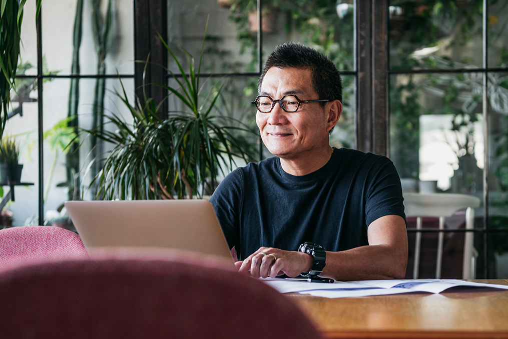 Commit to Getting Financially Fit in 2020_mature asian man sitting at a table reviewing his retirement plan with laptop