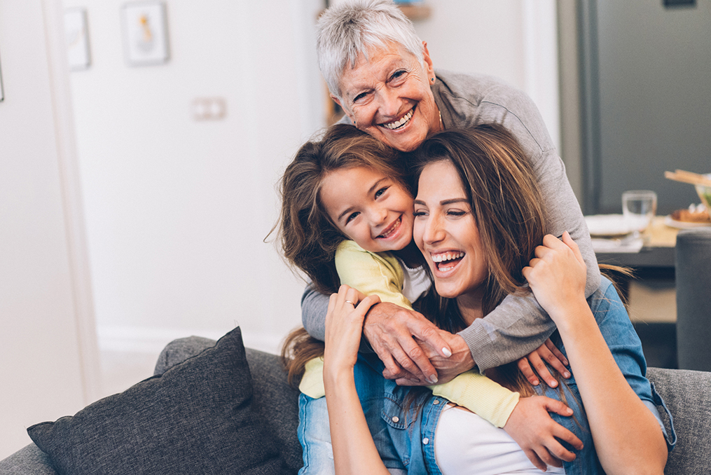 Financial Literacy Lessons for All Ages_Multi generational family sitting on couch hugging and laughing