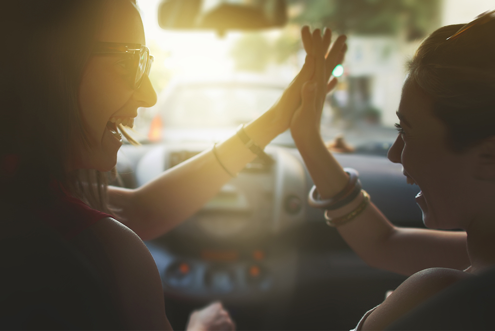 How to Buy Your Next Car with Confidence_Two women sitting in their car laughing and giving high fives