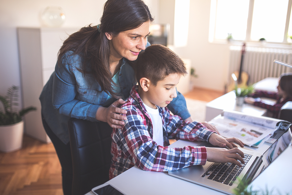 The Biggest Cybersecurity Questions for Parents_Mom encouraging son to use laptop