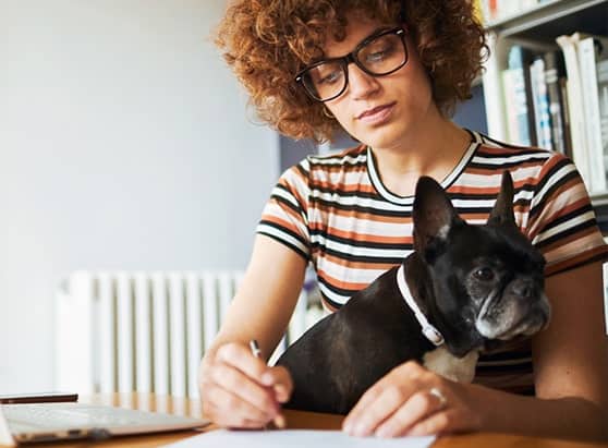 what-budgeting-method-is-right-for-you_woman-sitting-at-desk-taking-notes-with-dog-in-her-lap
