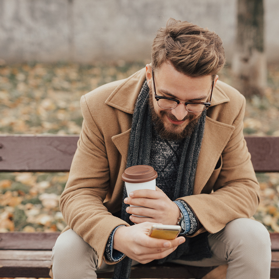 guy sitting at a park bench on his smart phone