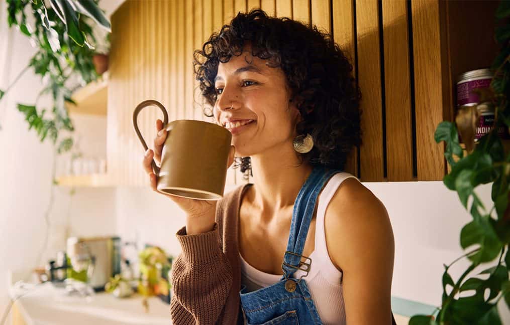 woman sitting in kitchen drinking coffee onpoint checking