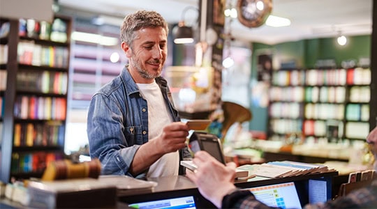 man checking out at book store with debit card onpoint checking