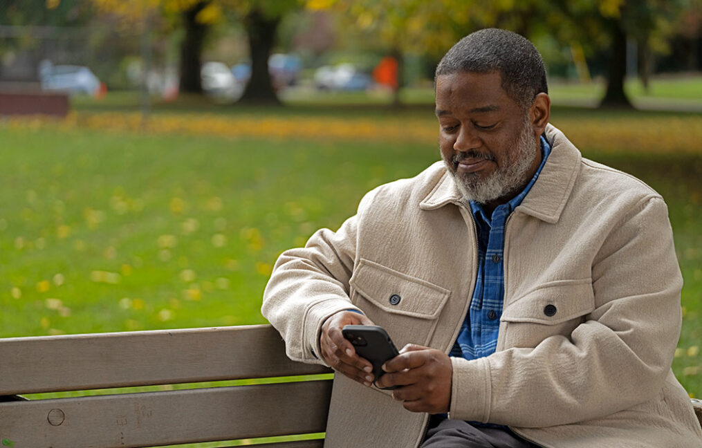 man on bench smiling at phone