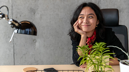 young woman sitting at her desk thinking about personal finances