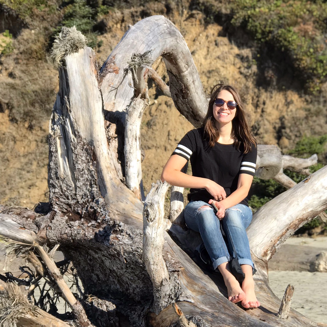 Abbygale sitting on driftwood at the beach
