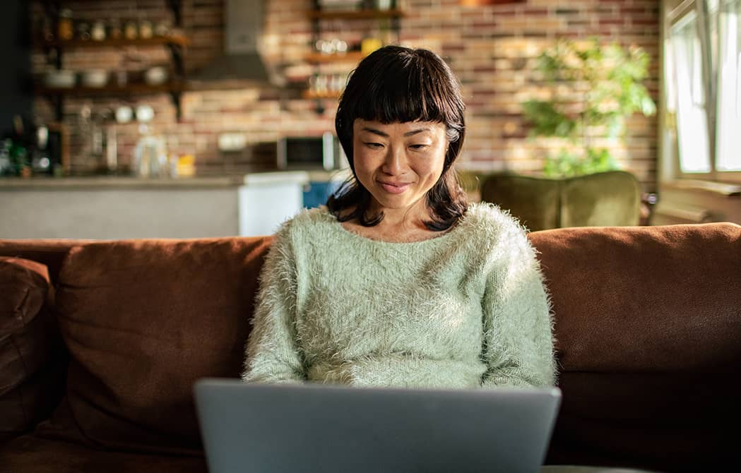 woman sitting on couch looking at laptop