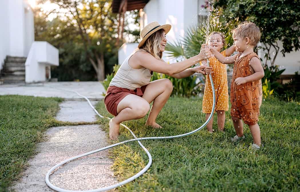 mom and kids playing outside with water