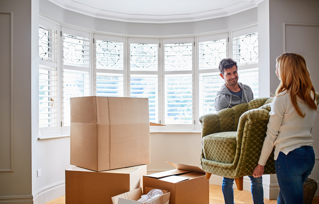 couple working together on moving a modern style couch into their new living room