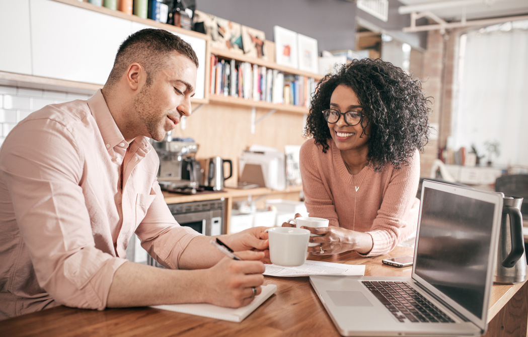 couple sitting together in their kitchen considering selling their home and buying a new one