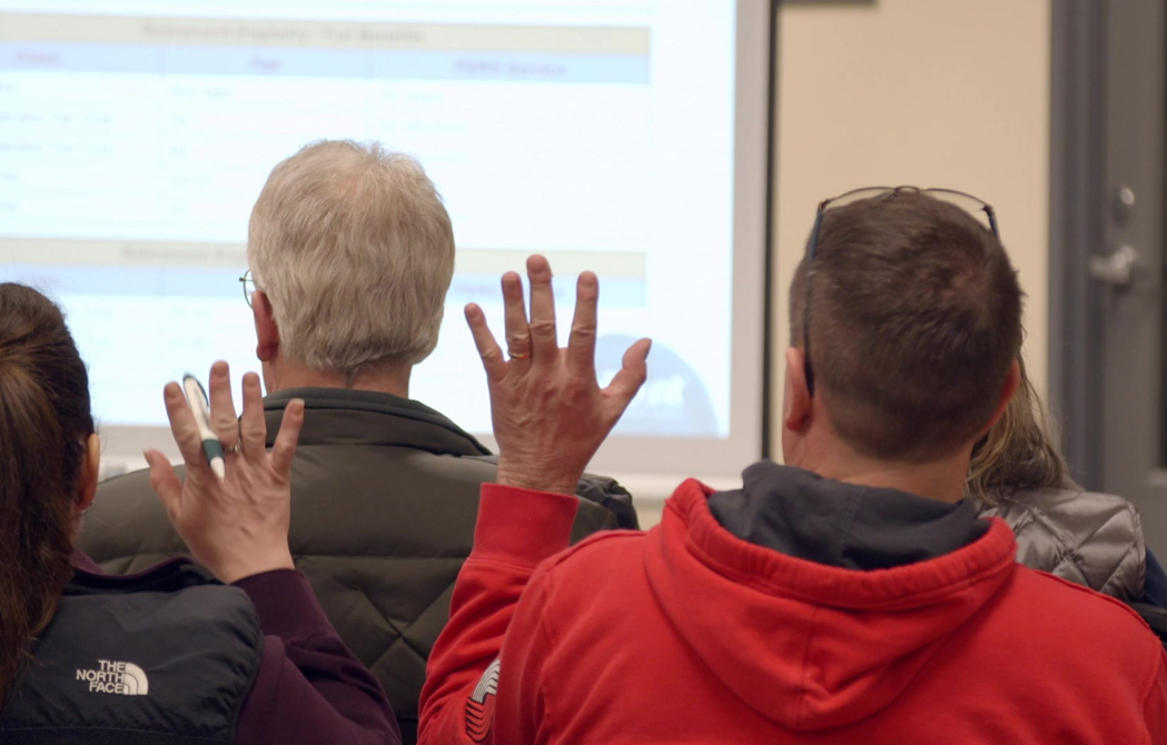 two seminar attendees raising their hands