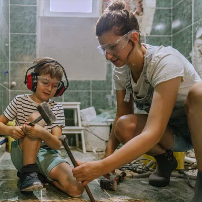 mom and son adding tile floor to the bathroom