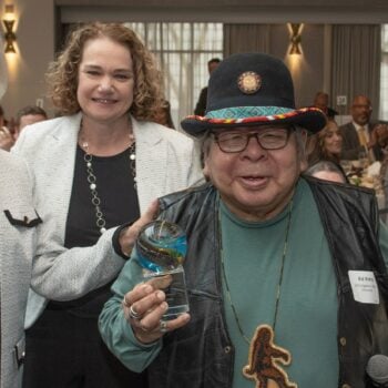 Member of Age+ Smiling Holding Up an Award