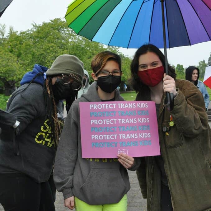 Three people holding signs to advocate for Basic Oregon Rights