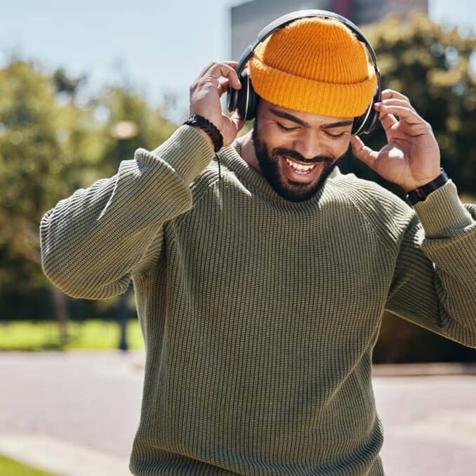 man with headphones wearing an orange beanie