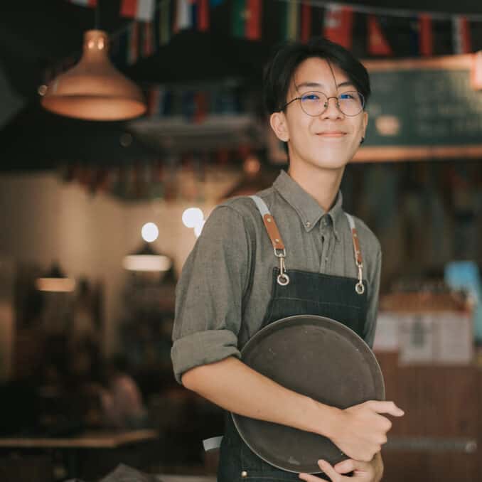 boy-waiter-looking-at-camera-smiling-work-at-cafe-opening