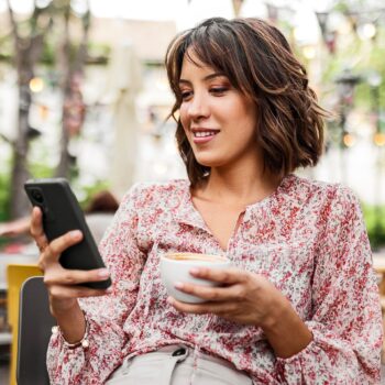 woman-on-her-phone-drinking-coffee-outside