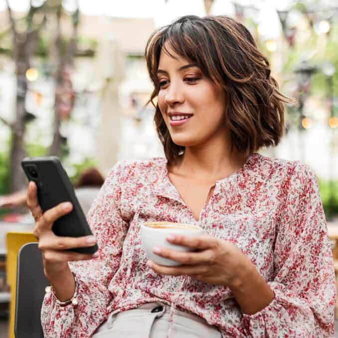 woman-on-her-phone-drinking-coffee-outside