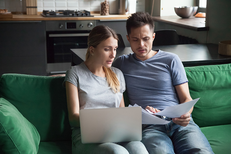 Worried couple calculating high domestic bills on laptop