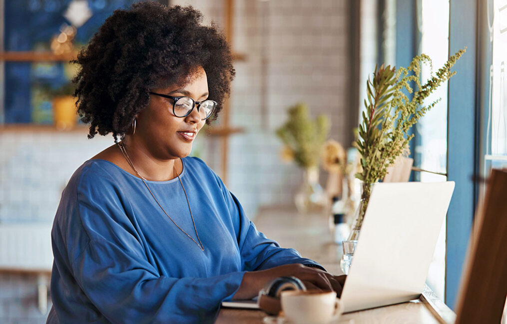 black woman researching on laptop in cafe