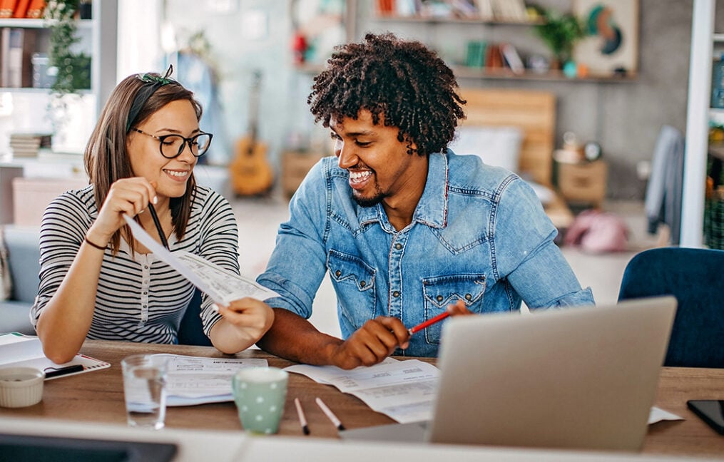 couple look over finances while at counter with laptop