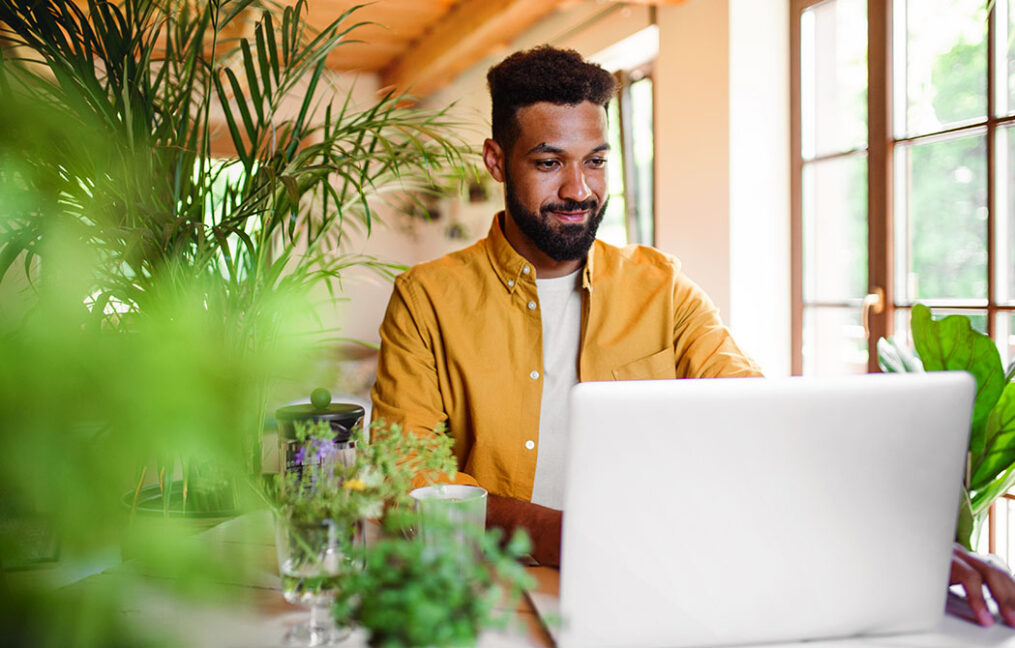 Man smiling while reviewing finances on laptop