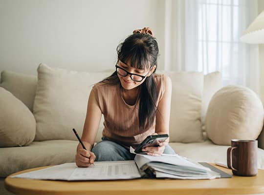 financial wellness onpoint community credit union budgeting education girl sitting on couch working on finances with glasses financial