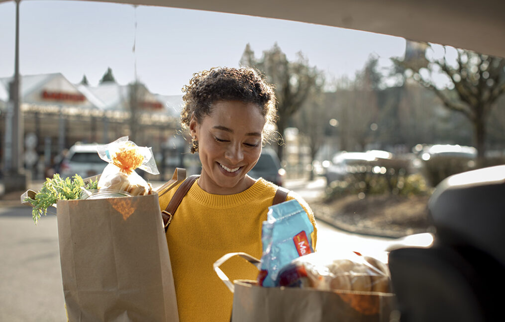 Woman packing groceries into the back of her car in a Fred Meyer parking lot.