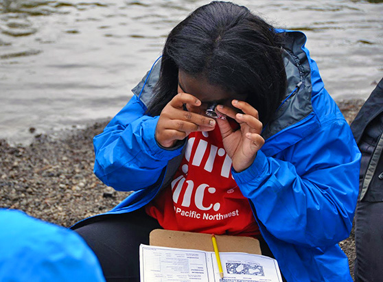 Girls Inc-girl inspects and records geological findings near river