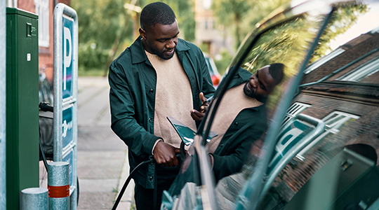 man charging his ev while looking at his phone