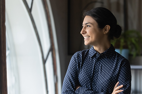 Woman crossing her arms smiling looking out window