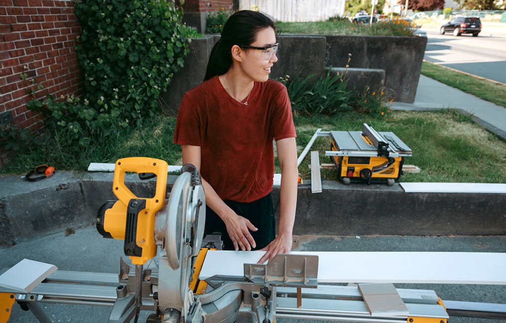 woman in driveway working with miter saw