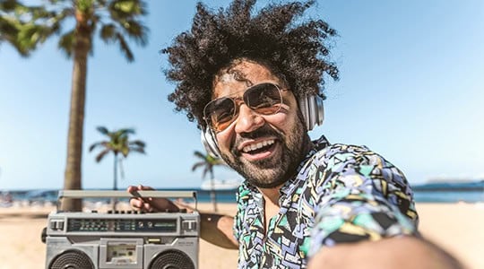 man on beach with boombox smiling on vacation taking a selfie onpoint heloc