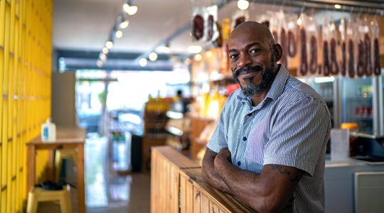 Business Checking-Business man standing behind the counter at a butcher shop