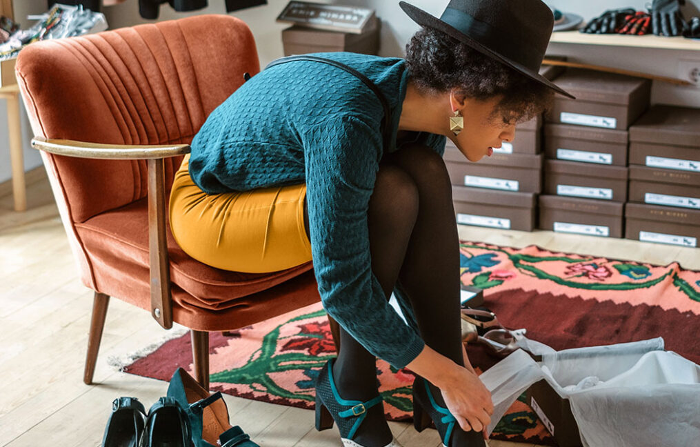 young woman in hat trying on shoes in shoe store