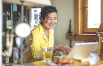 woman standing in her kitchen using a tablet