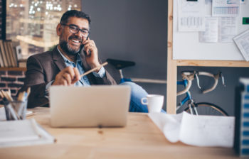 Man working in modern office holding a pencil and speaking on his cellphone
