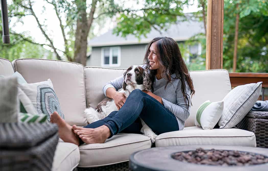 woman and dog sitting on couch by fireplace in backyard of home jon eisner homebuyer townhall may 12 2026 onpoint