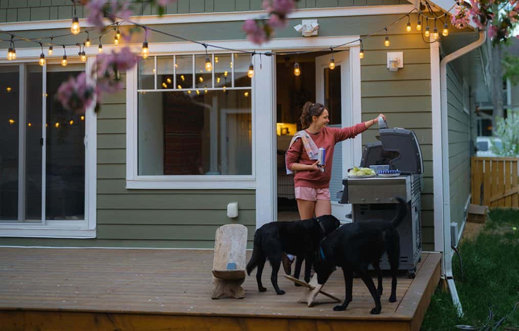 girl on porch with strig lights and dogs barbequing in spring onpoint homebuying seminar first time home