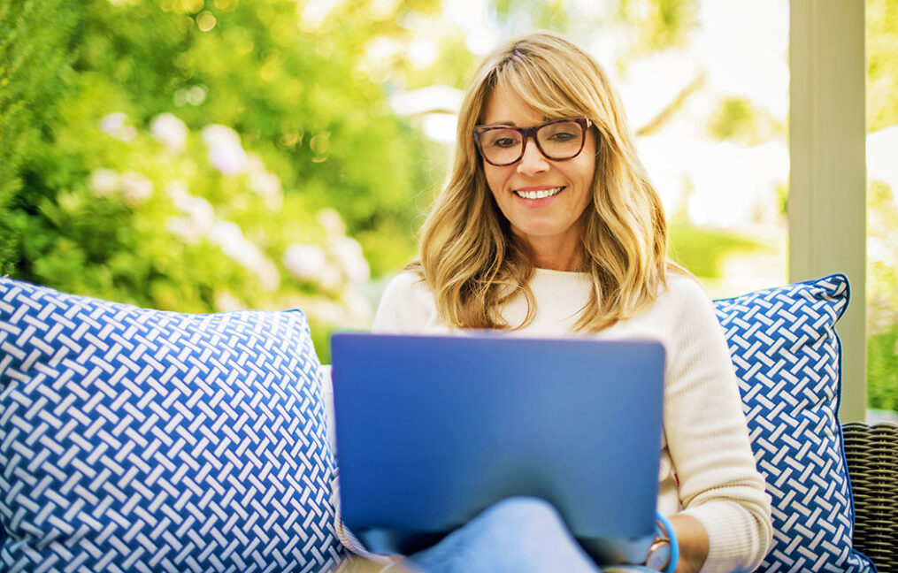 mature woman using laptop while sitting in the backyard at home