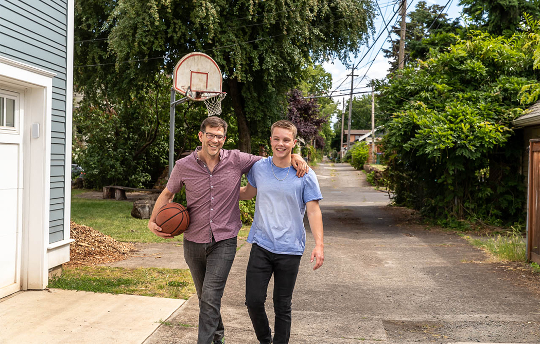 Father and son walking into their home after playing basketball together