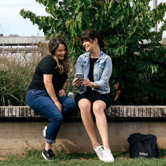 onpoint digital banking-two friends sitting outside in downtown portland sending money with zelle and OnPoint mobile app